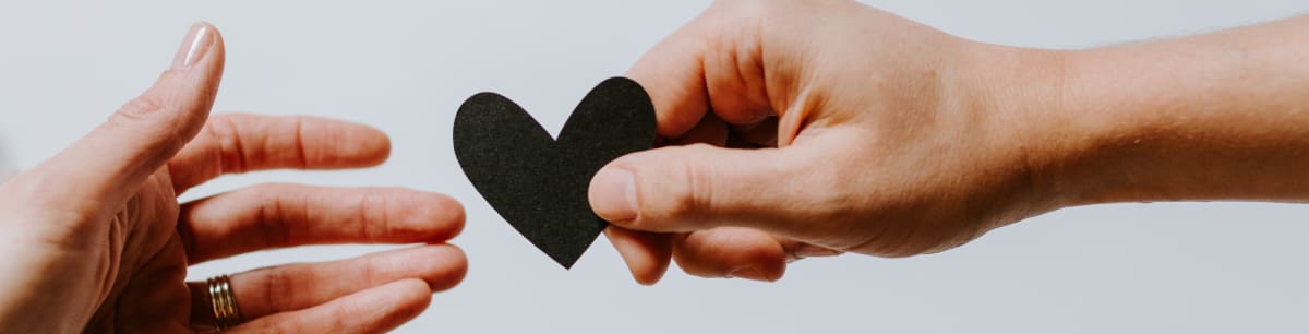 2 hands holding a black paper heart